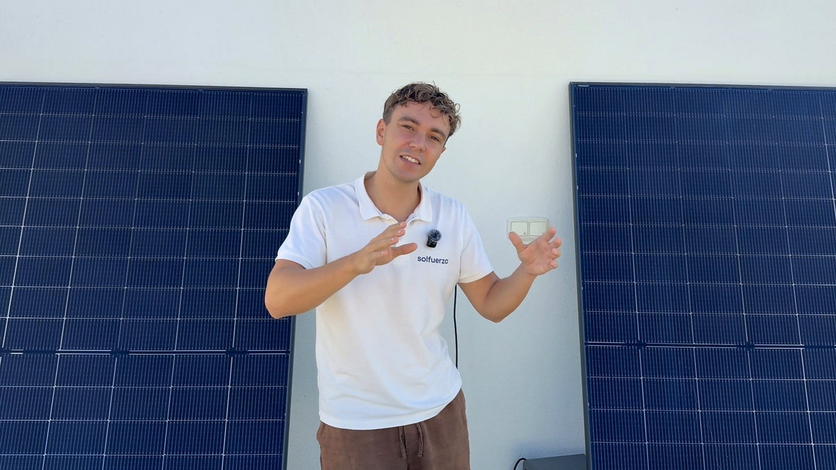 John von Solfuerza erklärt vor zwei Solarmodulen, wie viel ein Balkonkraftwerk spart